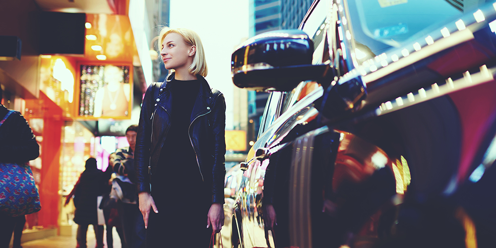 Young woman standing on the street next to a car