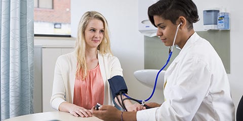 A female student having her blood pressure checked by a female doctor
