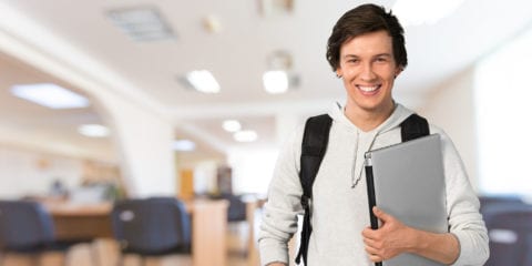 A young male holding a folder, looking at camera and smiling