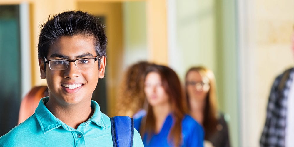 Friendly Indian high school student smiling in hallway