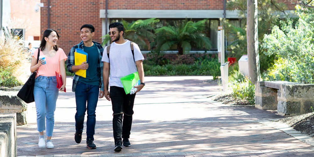 Three students walking to class, smiling
