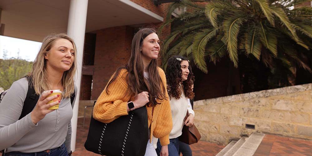 Female students with coffee walking on campus